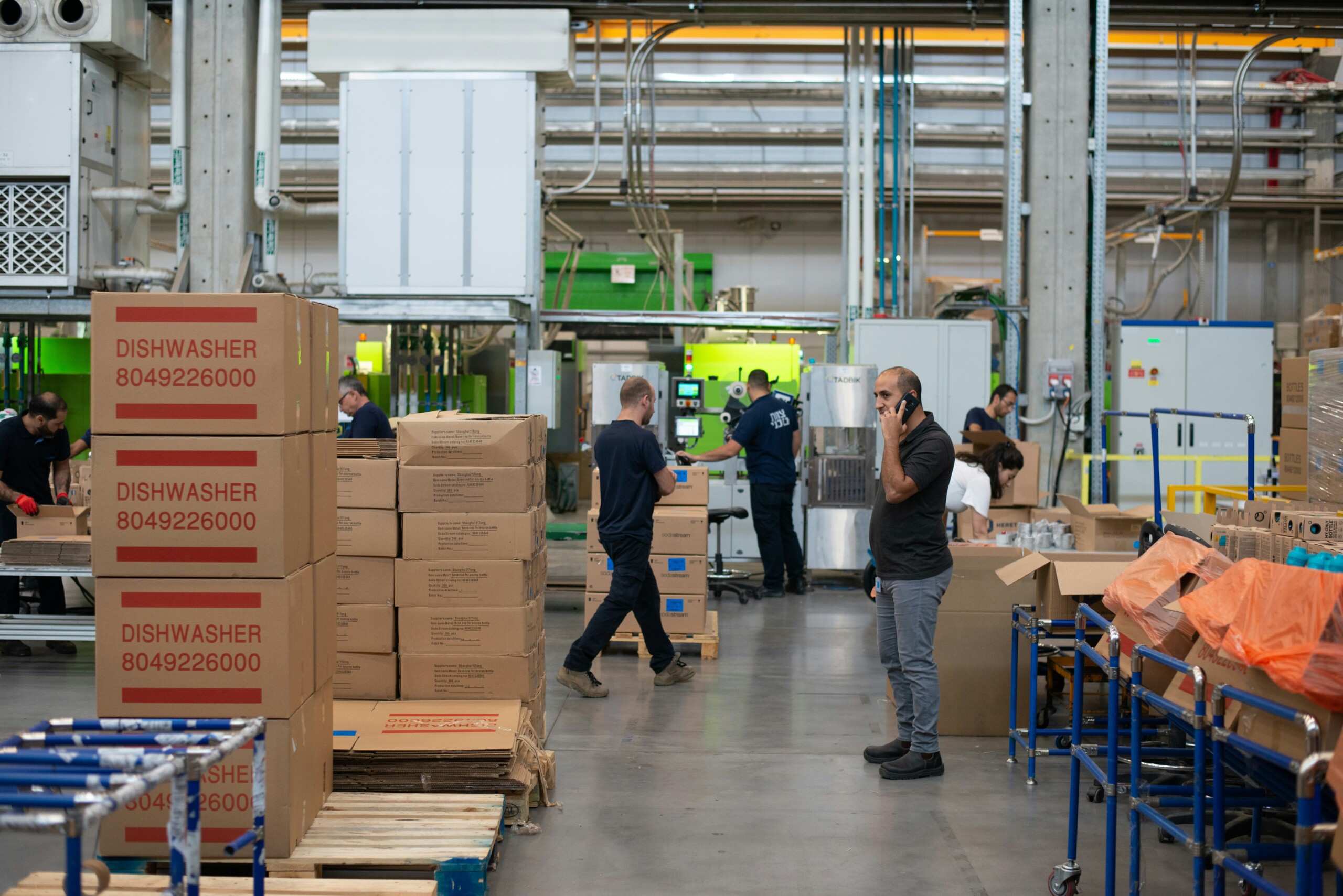Workers managing packaging and equipment inside a busy manufacturing warehouse. Workers managing packaging and equipment inside a busy manufacturing warehouse.