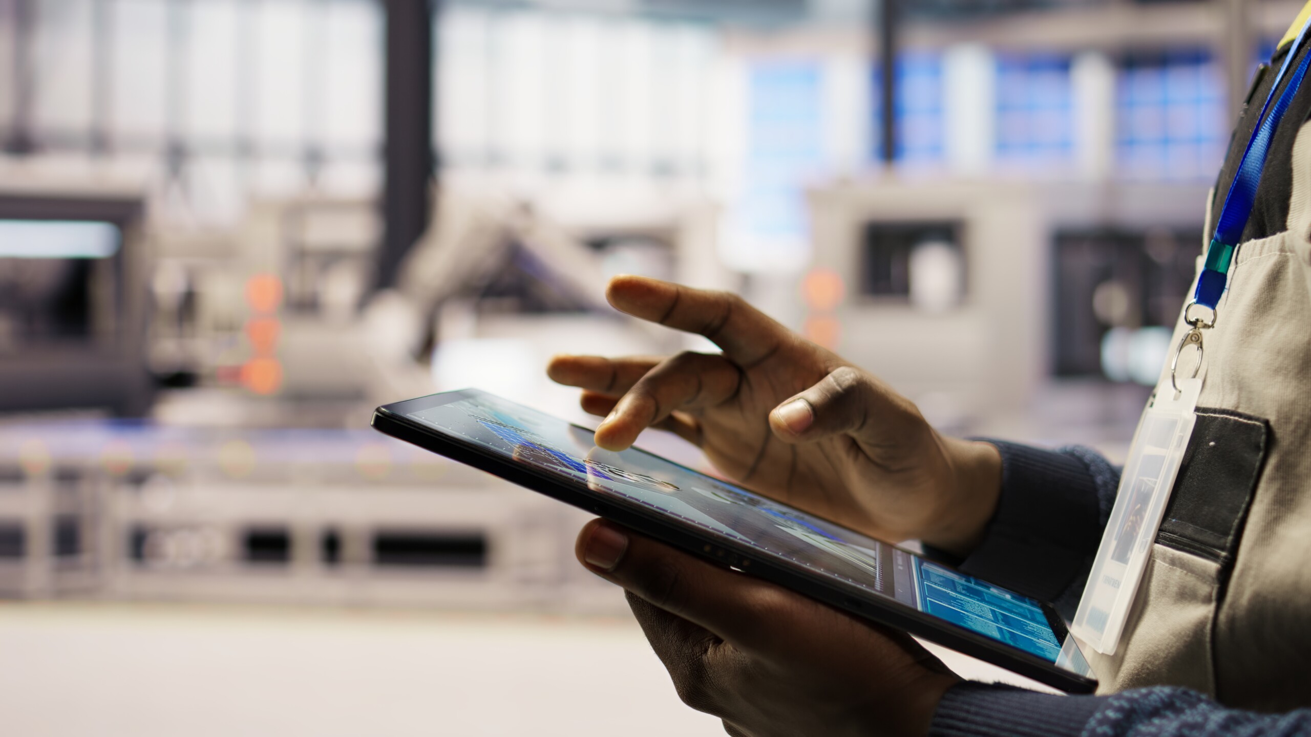 Technician using a digital tablet to monitor automated systems inside a manufacturing facility. Technician using a digital tablet to monitor automated systems inside a manufacturing facility.