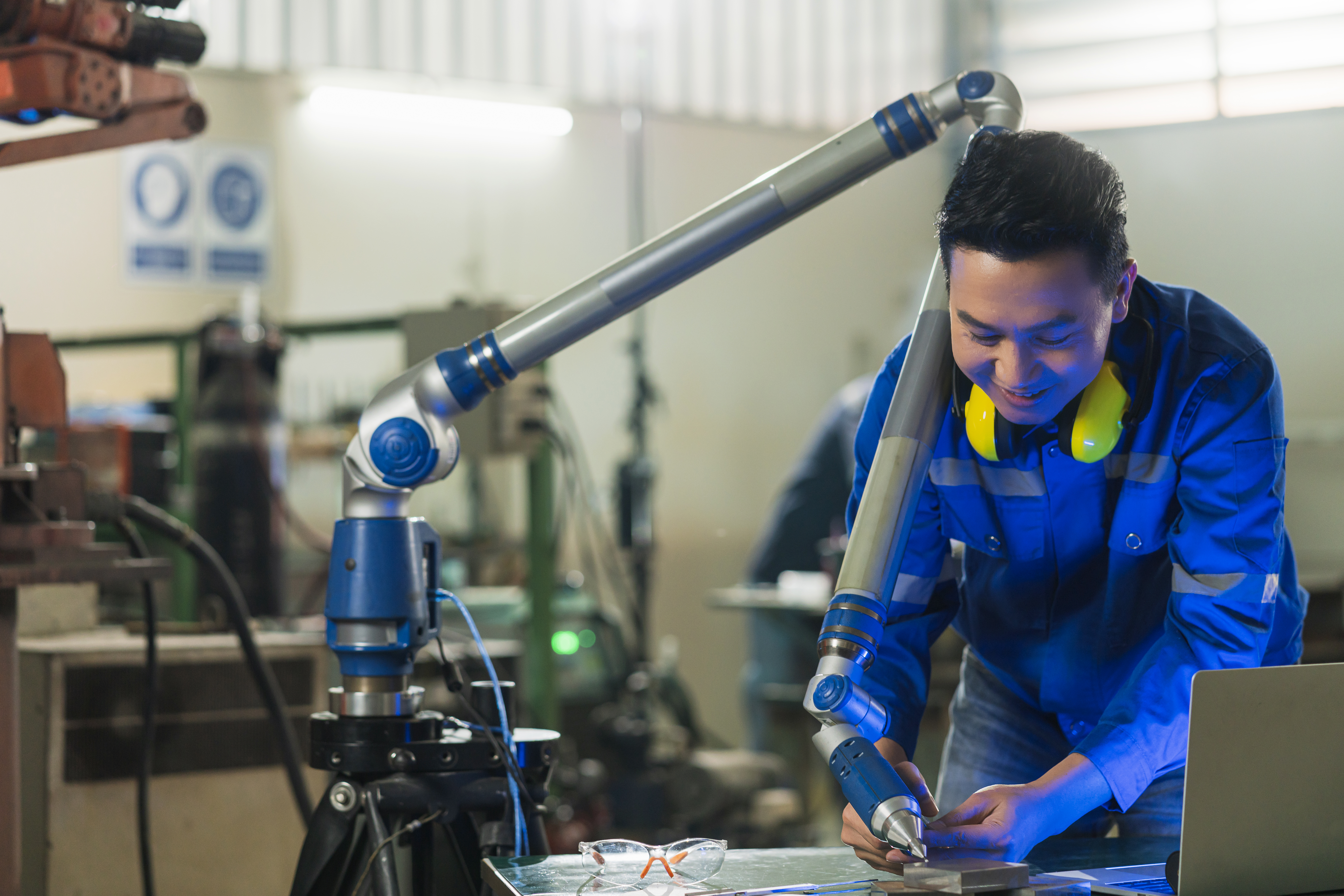 Engineer operating a robotic arm while testing equipment in a manufacturing lab. Engineer operating a robotic arm while testing equipment in a manufacturing lab.