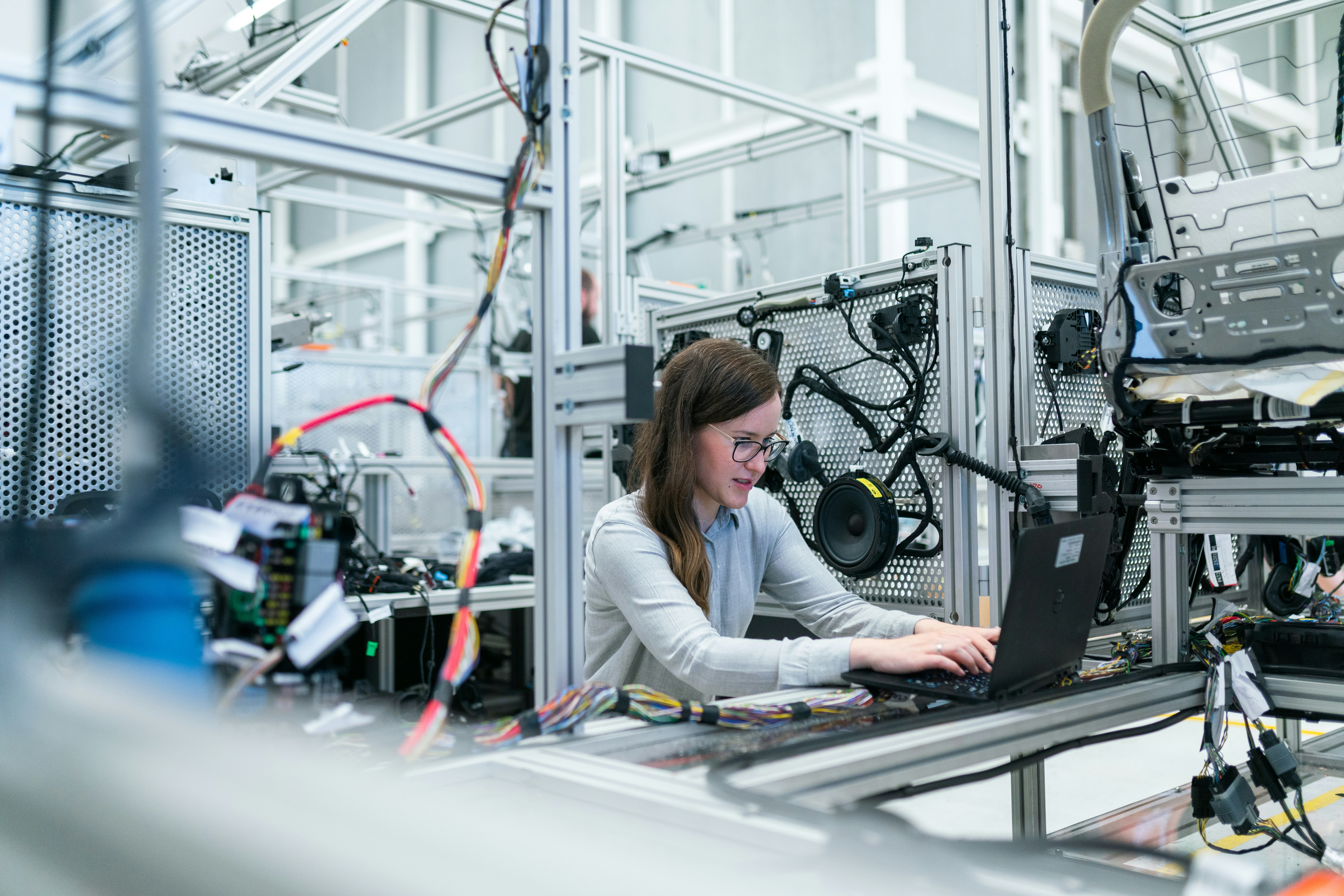 Engineer using a laptop to configure electronic systems in a manufacturing lab. Engineer using a laptop to configure electronic systems in a manufacturing lab.