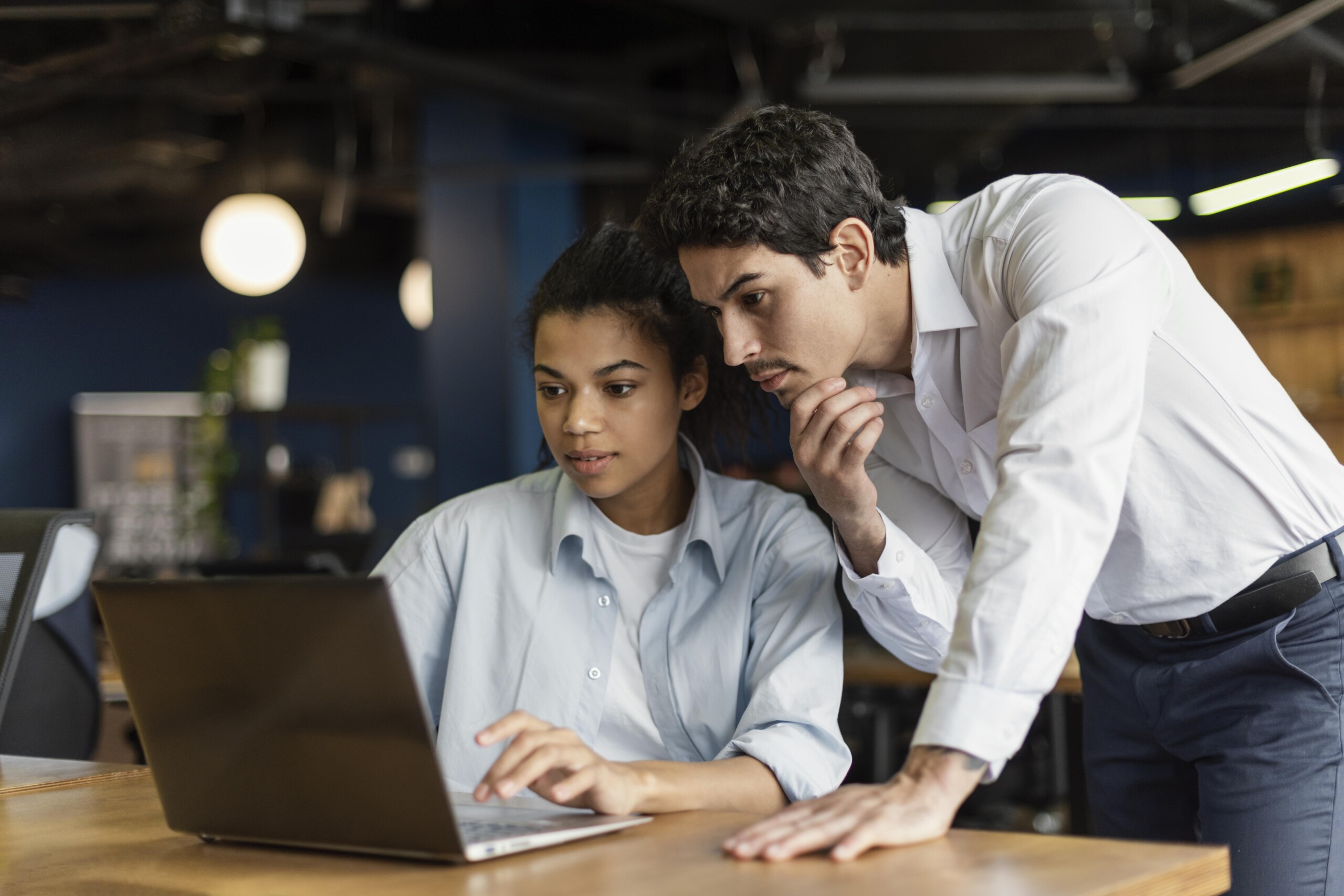 Two professionals collaborating on a laptop in a contemporary office environment.